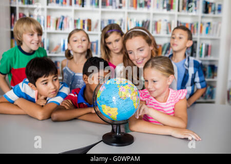 Enseignant et élèves looking at a globe Banque D'Images