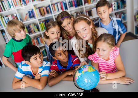 Enseignant et élèves looking at a globe Banque D'Images