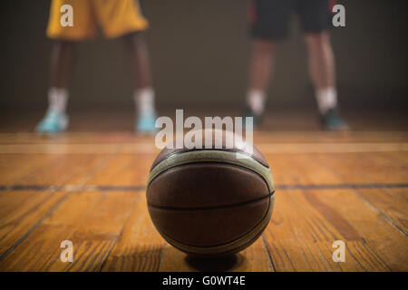 Close up sur le basket-ball mise sur le sol en face de joueurs de basket-ball Banque D'Images