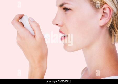 Image composite de jolie blonde femme asthmatique à l'aide d'inhaler Banque D'Images