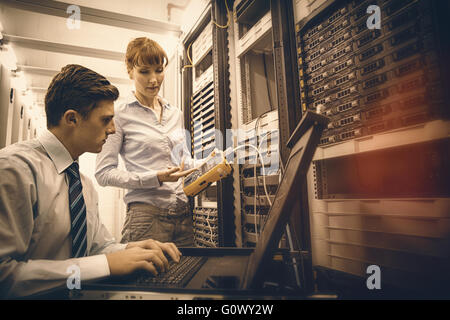 Équipe de techniciens à l'aide de l'analyseur de câble numérique sur des serveurs Banque D'Images