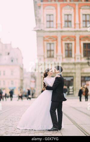 Heureuse mariée et le marié élégant exécutant serrant sur l'historique vieille ville ensoleillée Banque D'Images