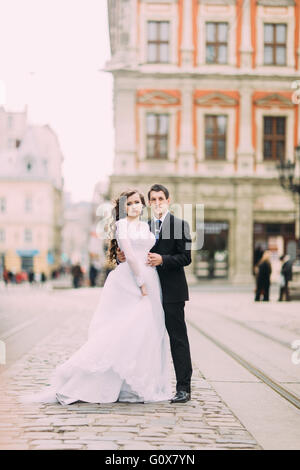 Heureuse mariée et le marié élégant exécutant serrant sur l'historique vieille ville ensoleillée Banque D'Images