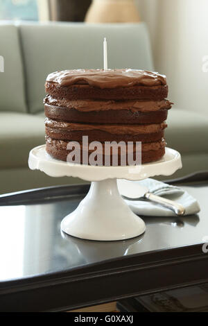 Gâteau au chocolat en couches avec Candle on Cake Stand sur table basse Banque D'Images