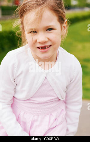 Portrait de 5 ans, fille en robe rose et blanc chandail, smiling at camera et montrant ses dents en avant Banque D'Images