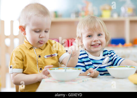 Deux drôles smiling little kids de manger dans le jardin d'enfants Banque D'Images
