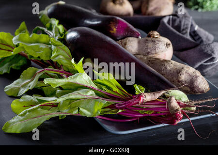 Betterave, aubergines et de feuilles de betterave sur la plaque avec un chiffon sombre Banque D'Images