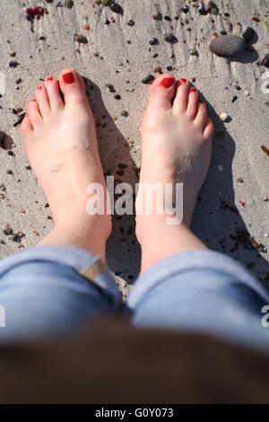 Les pieds nus avec des ongles peints en rouge sur une plage sur Iona, Argyll, Scolant Banque D'Images