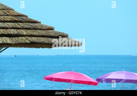 Plage avec parasols réalisés avec le bambou et la paille dans le luxueux resort Banque D'Images