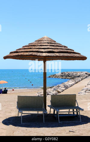 Plage avec parasols réalisés avec le bambou et la paille dans le complexe par la mer Banque D'Images