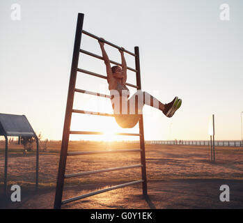 Longueur totale shot of young woman exercising on wall bars avec ses jambes. Femme Fitness exercer son abs avec jambe de suspension rais Banque D'Images