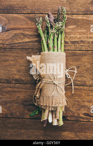 Bande d'asperges fraîches enveloppée de tissu en lin sur table en bois Banque D'Images