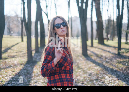 Portrait d'un hipster woman standing in woodland faire signe shaka Banque D'Images