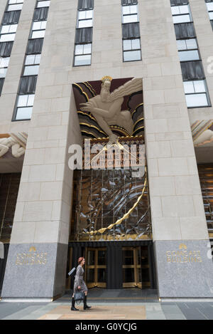 Femme en passant devant l'entrée avant de le Rockefeller Center / Comcast Building à New York City avec soulagement art déco Banque D'Images