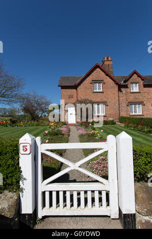 Village de Aldford, Angleterre. Printemps pittoresque vue d'une succession d'Eaton house gérés sur Aldford's School Lane. Banque D'Images