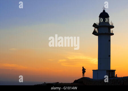 Le coucher du soleil. Jolie femme à contre-jour phare du Cap de Barbaria, à Minorque, Îles Balears. L'Espagne. Phare du Cap de Barbaria formentera road. Banque D'Images