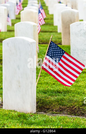 Lignes en granit blanc des pierres tombales militaires et des drapeaux américains dans le cimetière d'anciens combattants militaires. La verticale. Banque D'Images