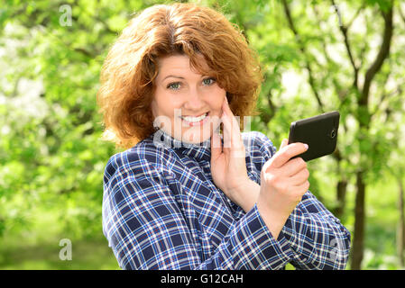 Woman using cell phone in park Banque D'Images