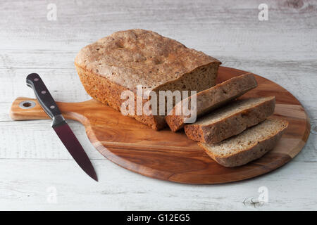 Pain de seigle noir maison surdough sur planche à découper en bois avec couteau de cuisine Banque D'Images