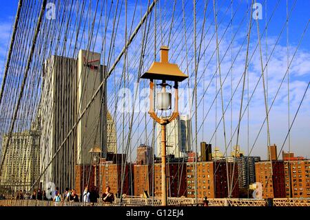 La ville de New York : Les personnes qui traversent le pont de Brooklyn avec son dédale de câbles de suspension Banque D'Images