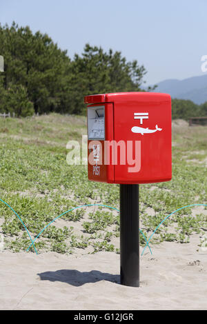 Japonais rouge mail box sur une plage de sable fin Banque D'Images