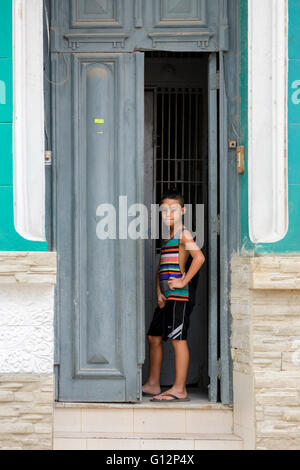 Un jeune garçon se tient dans l'embrasure d'un d'une maison dans le centre de La Havane, La Havane, Cuba Banque D'Images