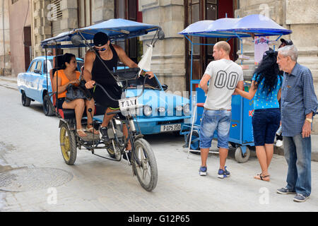 Les vitesses d'un vélo-pousse les clients passés à un décrochage en glace à la vieille Havane, La Havane, Cuba Banque D'Images