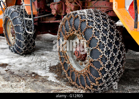 Les chaînes à neige sur les pneus de tracteur chasse-neige dans la neige Banque D'Images
