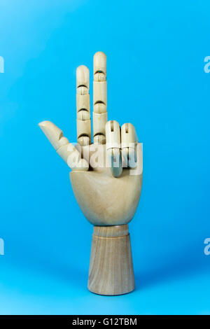 Bois à la main, main en bois, trois doigts, sur fond bleu Banque D'Images