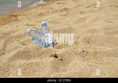 Le froid de l'eau potable dans des bouteilles transparentes sur la plage de sable par la mer Banque D'Images