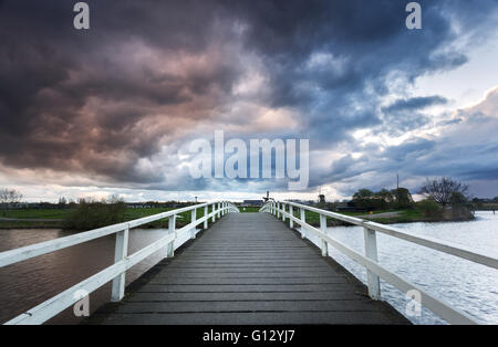 Beau pont de bois sur le fond de ciel nuageux spectaculaires au coucher du soleil dans le célèbre Kinderdijk, Pays-Bas Banque D'Images