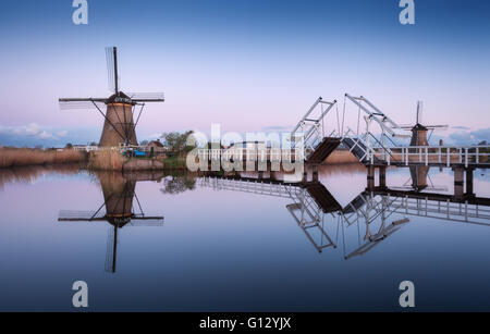 Paysage de printemps avec de beaux moulins à vent hollandais traditionnel près de l'eau canaux avec reflet dans l'eau à l'aube Banque D'Images