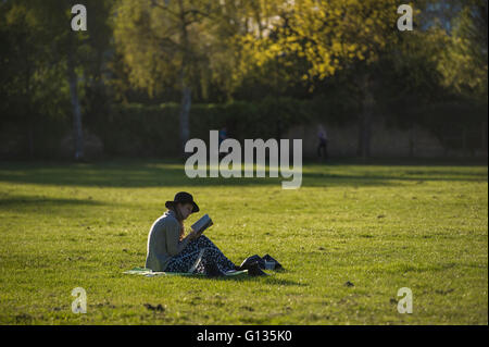 Une fille dans un floppy hat jouit de son livre sous le soleil dans un parc de Londres Banque D'Images