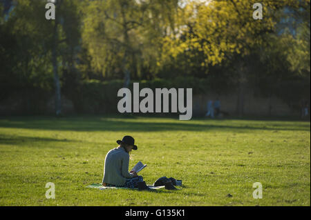 Une fille dans un floppy hat jouit de son livre sous le soleil dans un parc de Londres Banque D'Images