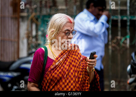 Femme indienne se penche sur son téléphone portable à l'extérieur du Temple de Kapaleeshwara, Mylapore, Chennai, Tamil Nadu, Inde Banque D'Images