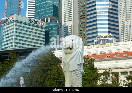Le Merlion Fontaine avec Fullerton Hotel de luxe et le quartier des affaires de Singapour derrière l'horizon.