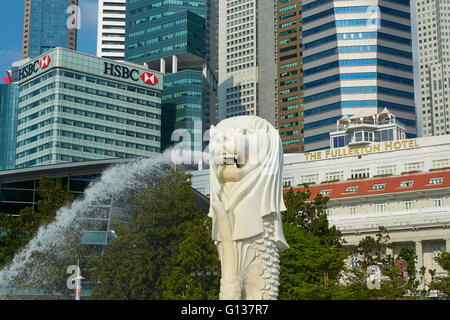Le Merlion Fontaine avec Fullerton Hotel de luxe et le quartier des affaires de Singapour derrière l'horizon. Banque D'Images