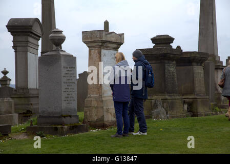 Jeune homme et femme se distingue respectivement en face de pierre dans la nécropole de Glasgow, Ecosse, Royaume-Uni Banque D'Images