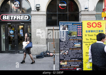 Un sans-abri dormant dehors sur BETFRED Gerrard Street dans le quartier chinois de Londres. Banque D'Images