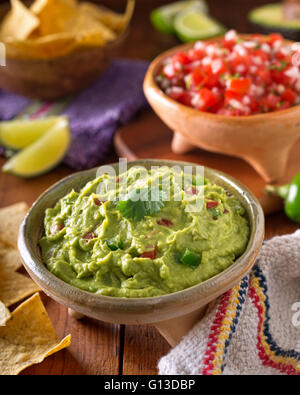 Un délicieux guacamole mexicain authentique avec dip, avocat, citron vert, coriandre, tomate et piment jalapeno. Banque D'Images