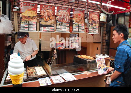 Un client en attente à la Crêpe japonais street kitchen (Imagawayaki) au marché Kuromon Ichiba, Osaka Banque D'Images