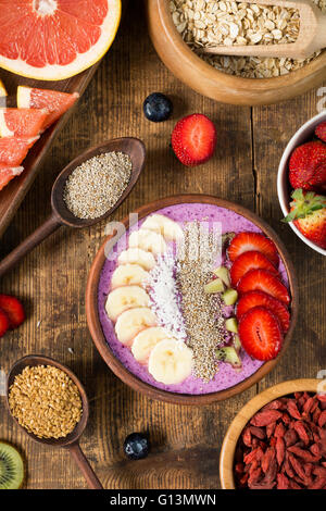 Smoothie Acai bowl garnie de graines de chia, flocons de noix de coco, banane, fraises et kiwi avec variété de l'air Banque D'Images