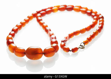 Chaîne de perles d'ambre antique pour une utilisation comme un collier sur un fond blanc réfléchissant