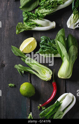 Assortiment de matières premières entières et tranchées petits bok choy (chou chinois), red hot chili pepper et lime plus vieux fond de bois. Da Banque D'Images