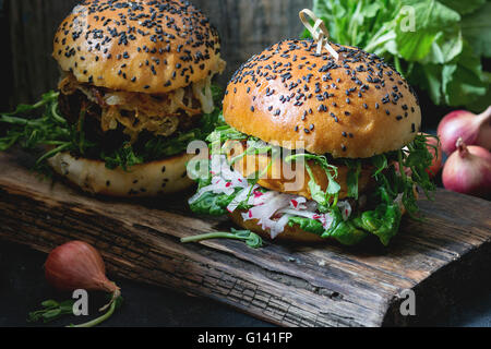 Deux des veggie burgers avec patate douce et de radis, choux, pois servi sur planche en bois en bois plus de background Banque D'Images