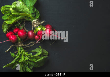 Bouquet de radis avec les feuilles sur fond noir, vue du dessus, copy space Banque D'Images