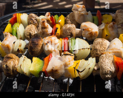 Brochettes de poulet et légumes en cours de cuisson sur un barbecue Banque D'Images