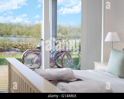 La vue depuis la chambre à coucher d'une maison de vacances à Lower Mill Estate près de Cirencester, à la cours des bicyclettes aux lacs au-delà Banque D'Images