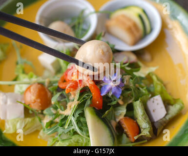 Oeuf de caille sur baguettes avec salade de légumes vert japonais sur l'arrière-plan Banque D'Images