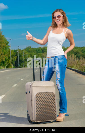 Randonneur femme positive avec grosse valise sur la route Banque D'Images